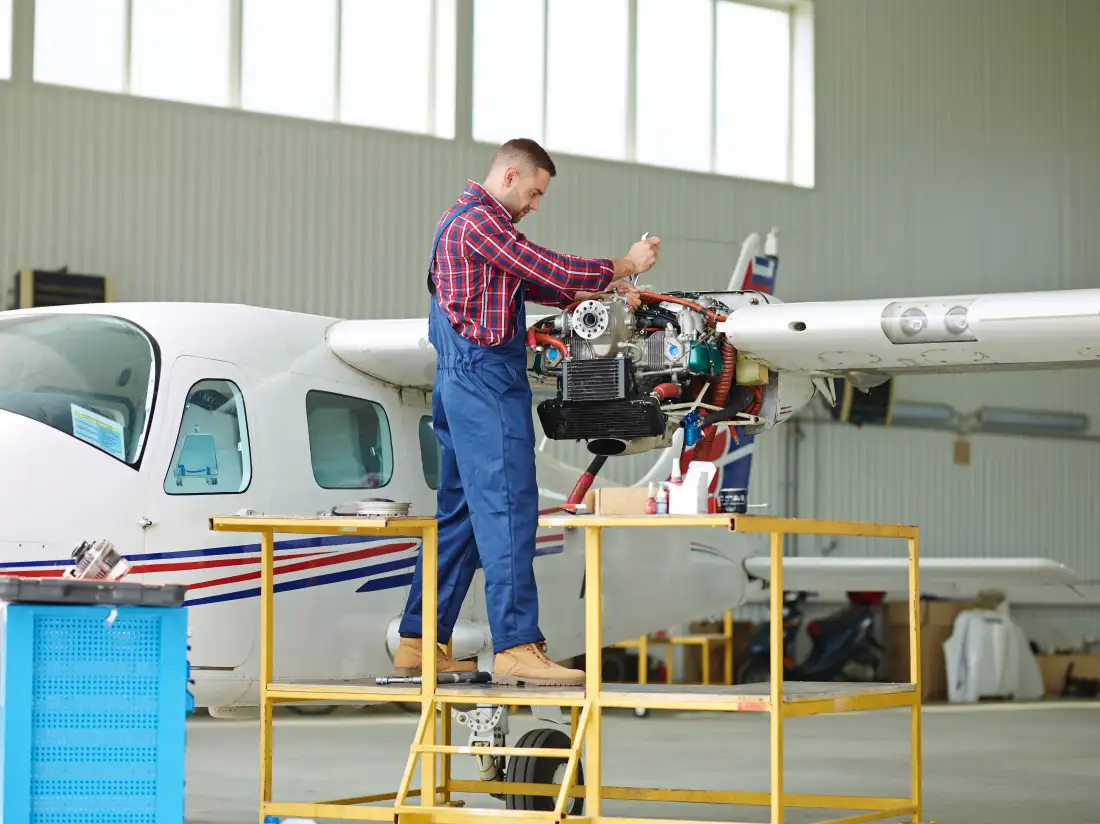 Aircraft maintenance engineer working on a light aircraft engine in a hangar