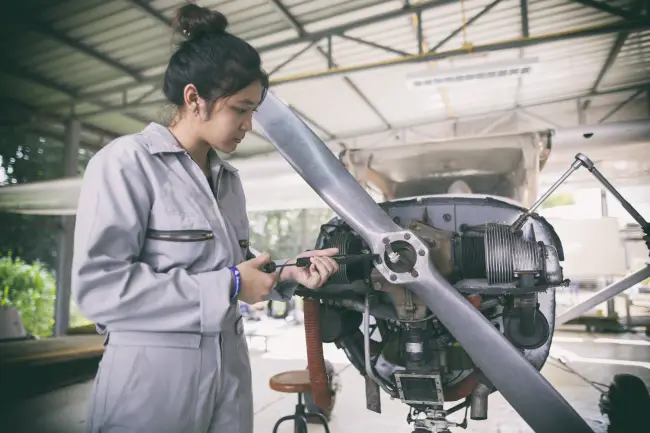 South Asian aircraft technicians performing non-destructive testing inspection on an aircraft structural panel