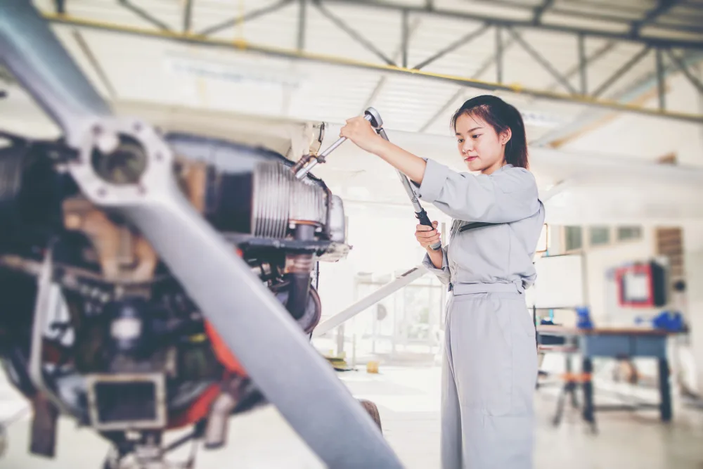 Pakistani aviation training student receiving hands-on mentorship from an instructor inside a maintenance hangar