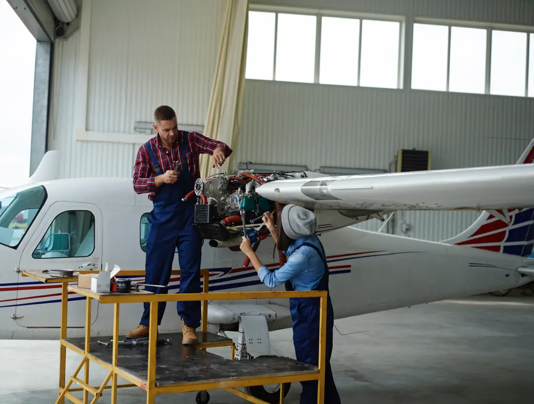 Team of aircraft maintenance engineers discussing a maintenance task and handover in a hangar