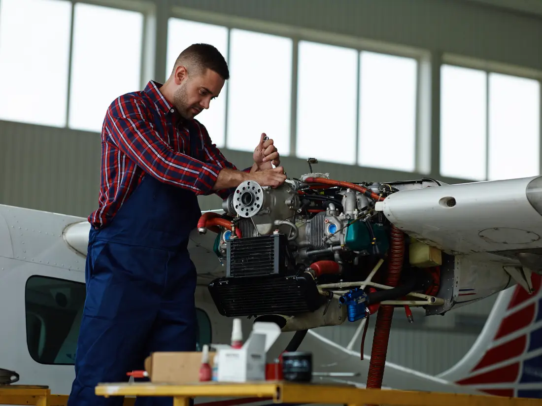 Aircraft maintenance engineer using technical skills to inspect a jet engine in a hangar