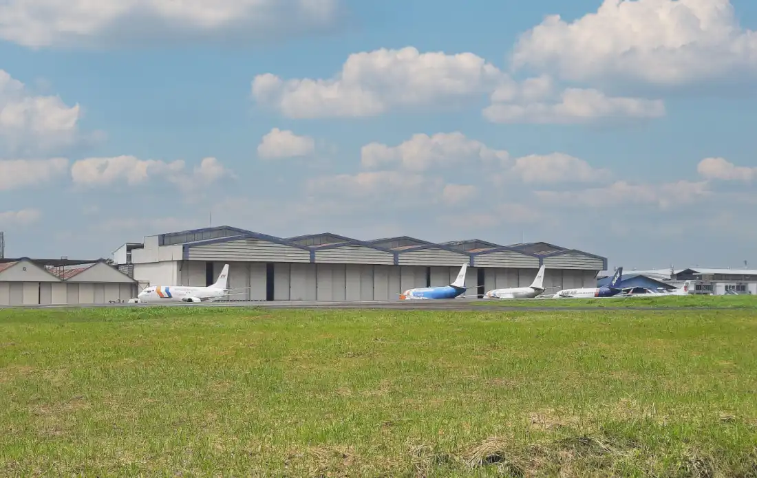 Several aircraft parked outside a maintenance hangar on an airport apron