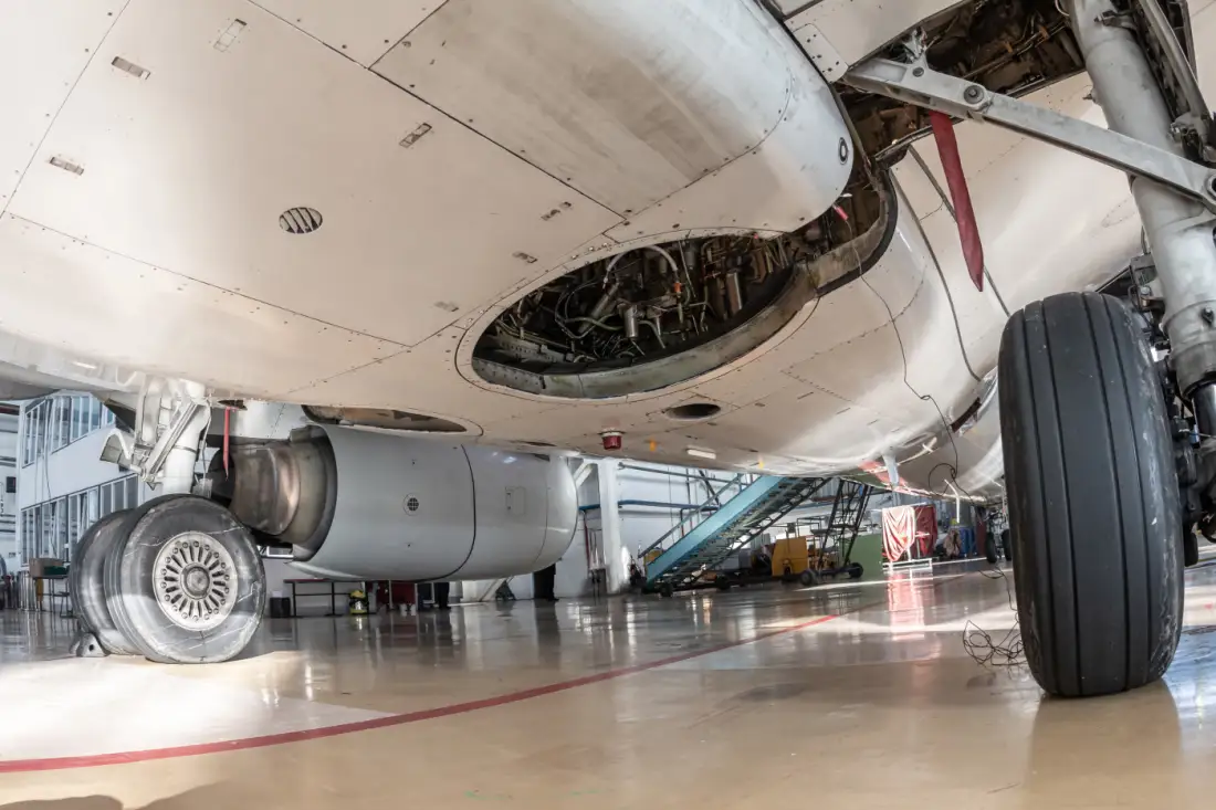 Close-up of the main landing gear and lower fuselage of a white passenger aircraft