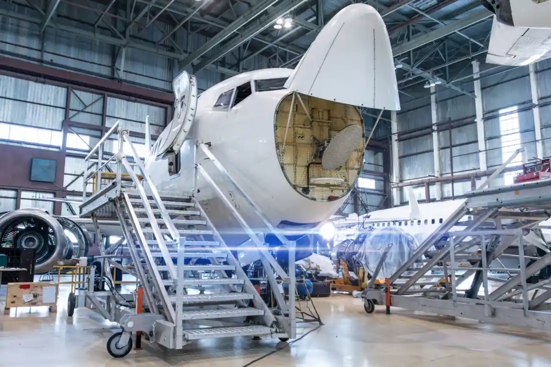 White passenger airliner under maintenance in an aircraft hangar with its nose weather radar open