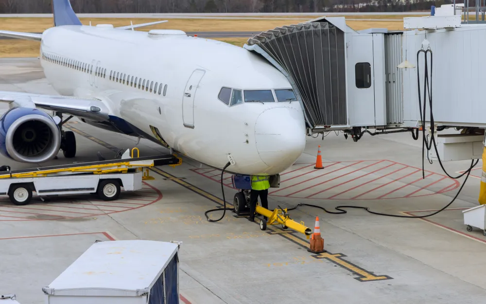 Passenger airliner parked at an airport gate with a ground service vehicle on the apron