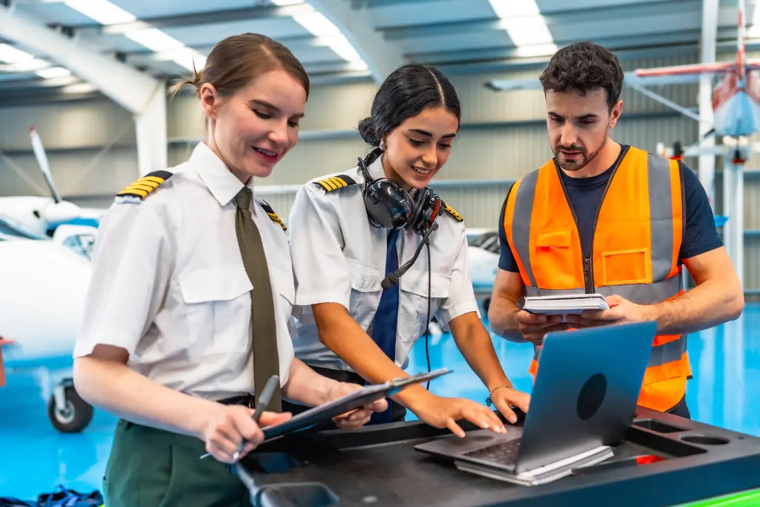 Aviation trainees using a laptop and tablet to check an aircraft in a hangar