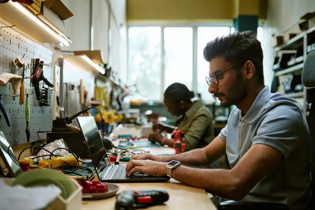 Engineering student working on a laptop in a technical workshop