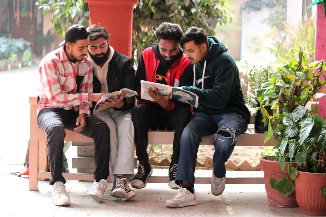 Group of students reading and studying together on a campus bench