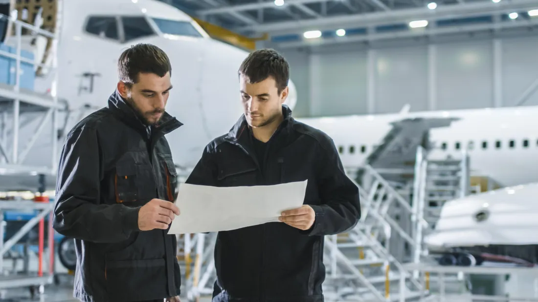 Engineers reviewing a document in an aircraft hangar
