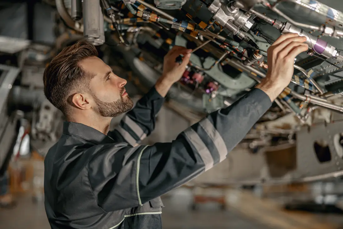 Aviation mechanic checking aircraft engine components in a repair hangar