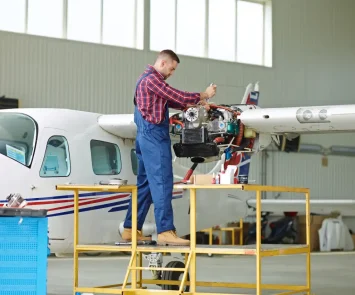 Aircraft maintenance engineer working on a light aircraft engine in a hangar