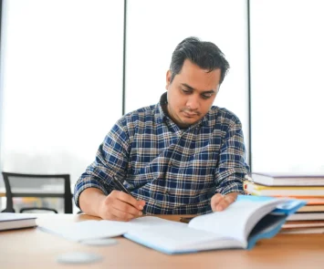 South Asian student studying at a desk with open books